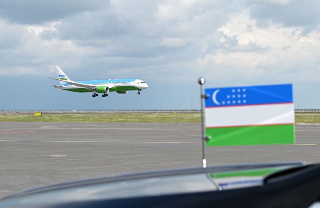 Uzbekistan's Boeing 787 aircraft landing at the background of Uzbeki flag